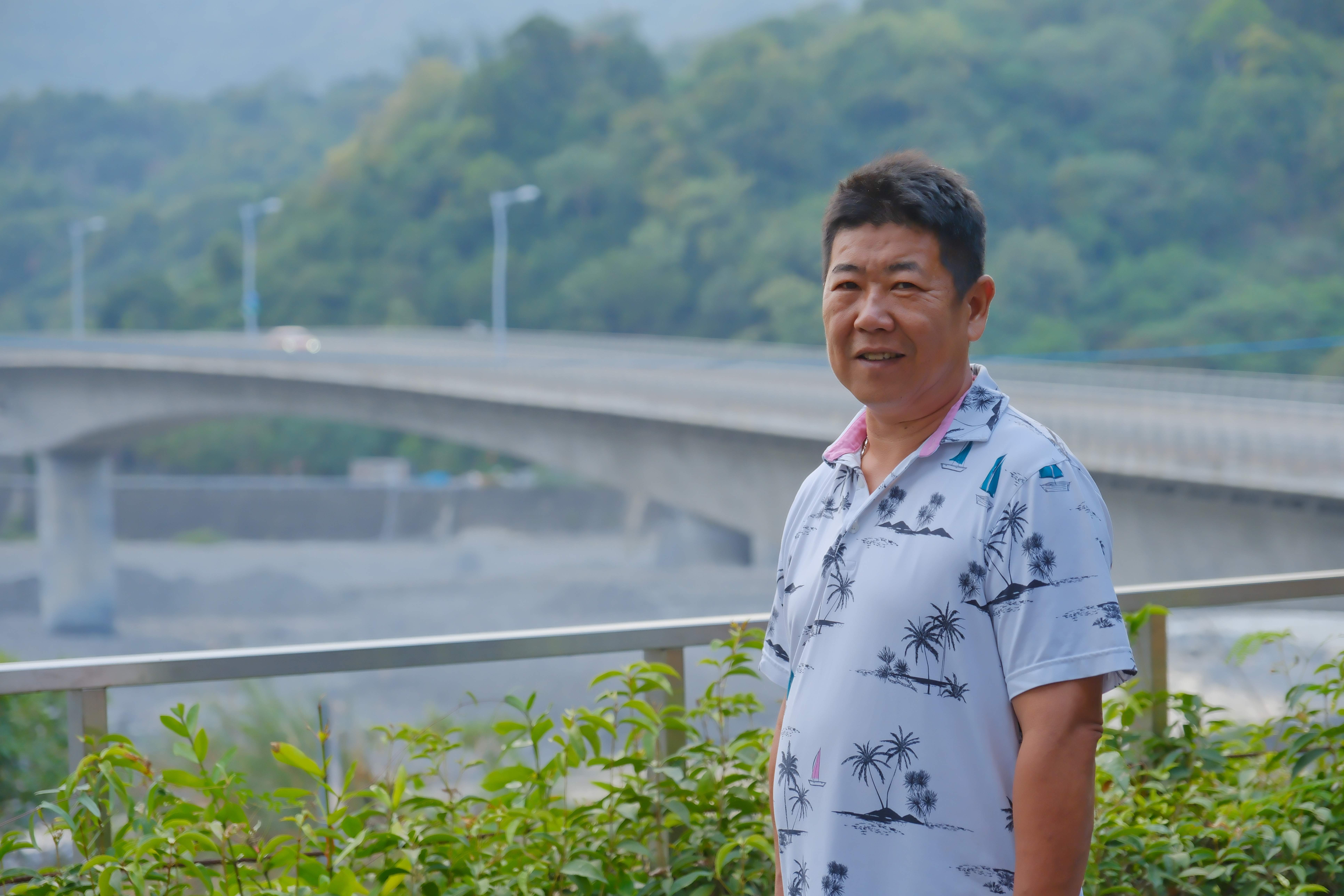 協會理事長簡銘辰在街區借問站暢聊寶來點滴，背景為寶來一橋。