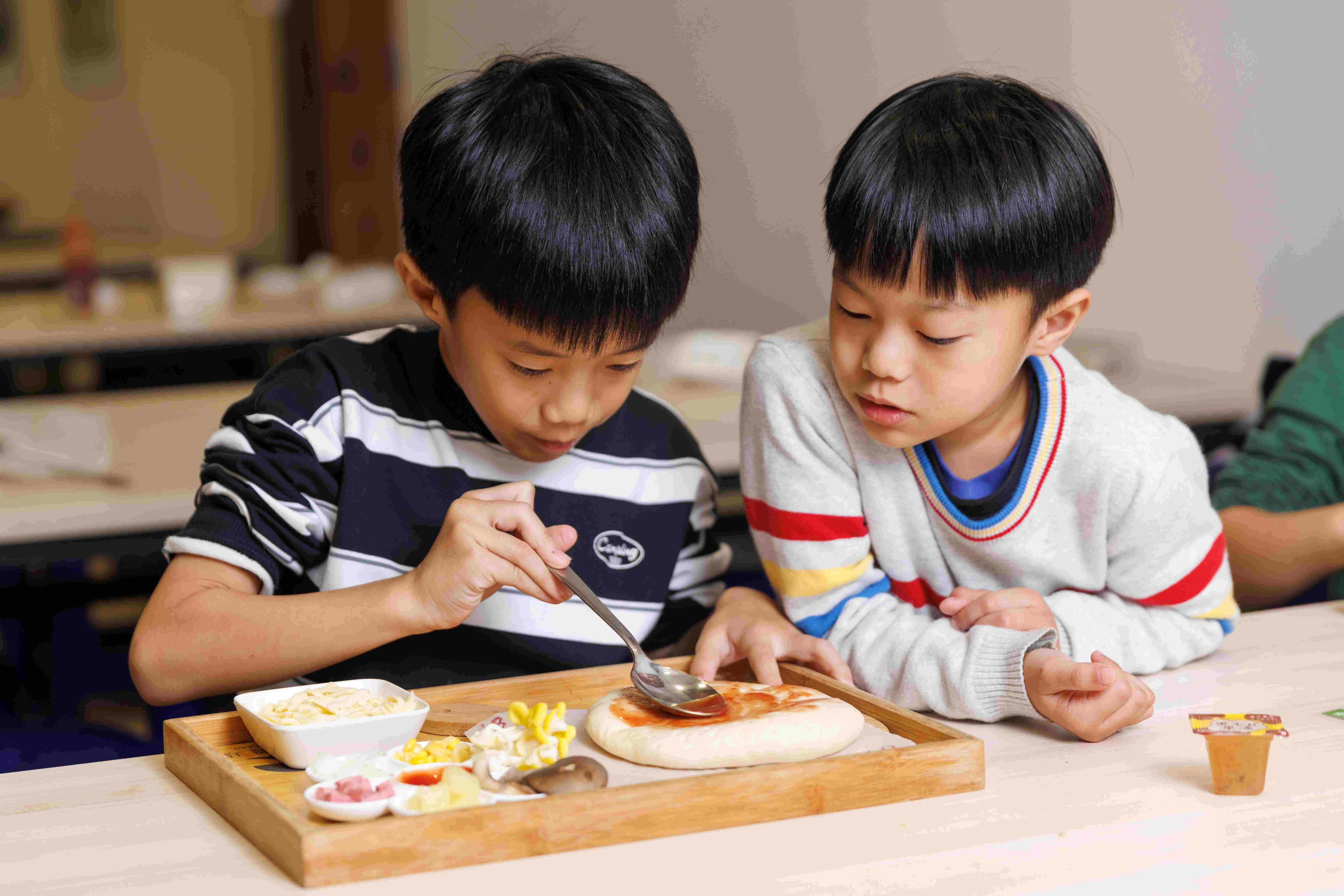 現做的PIZZ課程相當受歡迎，小朋友專注地堆疊各種食材，體驗動手做的樂趣。